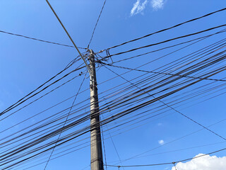 Electric Utility Pole with Numerous Power Lines Under Bright Blue Sky