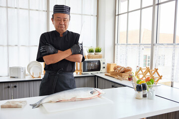 chef holding knife with a big raw salmon in the kitchen