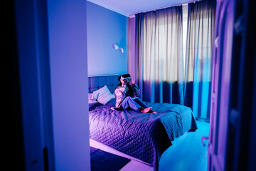 Young woman enjoys immersive gaming experience in neon-lit bedroom setting