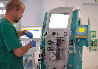 Doctor preparing dialysis machine for patient treatment in hospital room