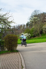 Couple enjoying a leisurely bike ride through a serene park surrounded by blossoming trees and lush greenery in springtime