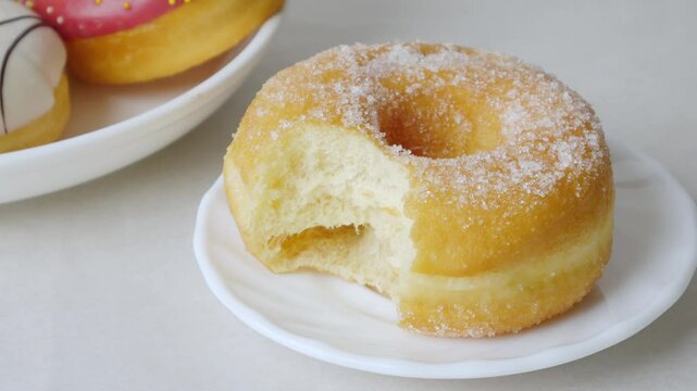 Donuts with sugar sprinkles with bite mark on a white background.