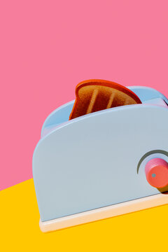 Toy toaster with toast on colorful background