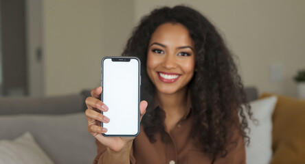 Fototapeta premium Smiling woman holding a smartphone with a blank screen indoors at home