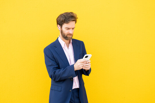Businessman using smartphone against yellow background
