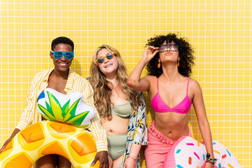 Multiracial women in bikinis holding inflatable rings