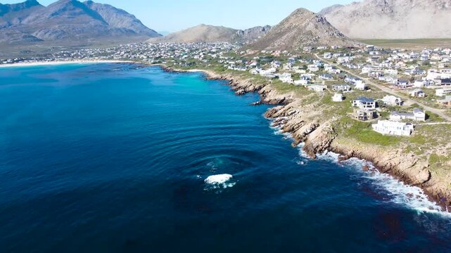 Camera panning up along the coast of the small town of Pringle Bay, 4K aerial video