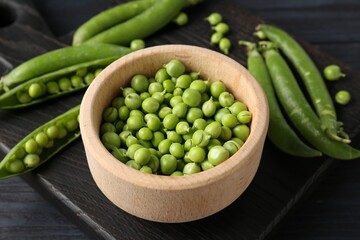 Fresh ripe green peas on black wooden table, closeup