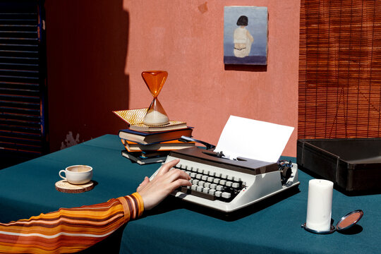 A nostalgic workspace with a mechanical typewriter and hourglass on a desk