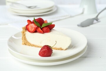 Piece of tasty cheesecake with strawberries and mint on white wooden table, closeup