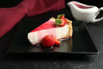 Piece of tasty cheesecake with strawberries, sauce and mint on black table, closeup