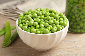 Fresh green peas in bowl, jar and pods on wooden table, closeup. Pickling vegetables