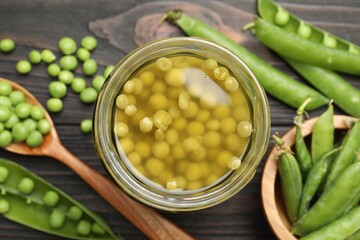 Pickled peas in jar and pods on black wooden table, flat lay