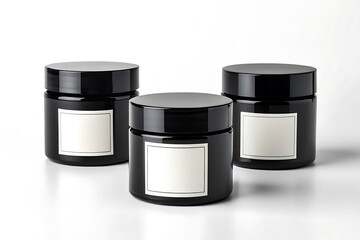 Three black cosmetic jars with blank white labels on a white surface studio product shot