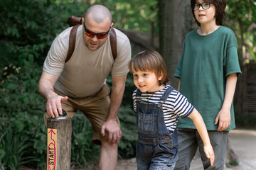 Father and sons getting ready for an outdoor challenge in the park. Real family bonding, excitement, and childhood energy in nature. Authentic lifestyle and parenting moment.
