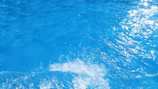 Video footage of blue clear water falling into a blue pool.