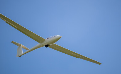 Segelflugzeug in der Luft vor blauem Himmel und weiße Wolken