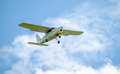 einmotoriges Flugzeug - Leichtflugzeug in der Luft vor blauem Himmel und weiße Wolken