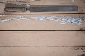 Large metal file placed at the top edge of a rustic beige wooden table. Space is left free for text...