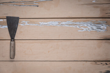Old putty knife placed on the left edge of a rustic beige wooden table. Space is left free for text...