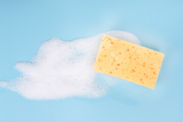 White pure foam with sponge for washing dishes on blue background. dishwashing foam close up
