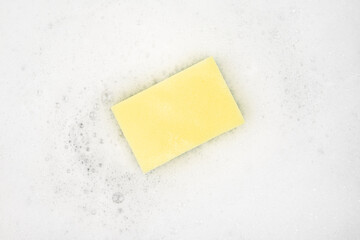 White pure foam with sponge for washing dishes. dishwashing foam and yellow sponge close up