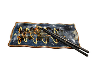 Used sushi plate with leftover sauce and chopsticks, capturing the realistic moment after a meal....