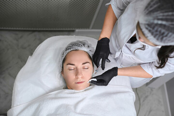 Young woman receives calming facial treatment in modern spa clinic. Serene ambiance, emphasized by...