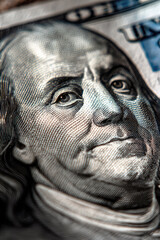 Close-up macro of Benjamin Franklin's face on a US hundred dollar bill, showcasing detailed security print features and textured engraving.