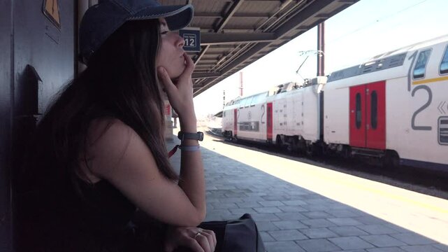 Woman waits pensively as train passes in Belgium