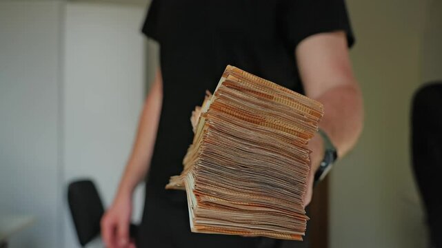 Slow motion of money lending concept as man offers thick euro bundle forward