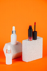 Mockup of black blank thin tube - mascara, lip gloss, gel, eyeliner, oil, etc. Cosmetic package with stylish props on orange background.
