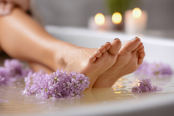 Woman's feet are in a tub of water with purple flowers