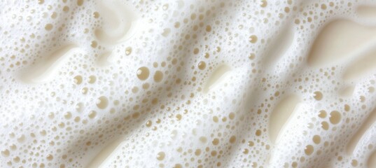 A Top-Down View of Creamy Milk Foam with Delicate Bubbles on a Soft White Background Surface