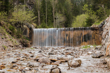 cascata e torrente di montagna con acqua che scorre tra le rocce, di giorno, in primavera, nelle...
