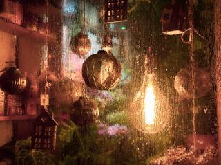 New Year's toys in a store window. Decorative ornaments hanging behind a frosted glass window  