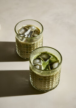 Top of view of two textured glass cups filled with iced matcha latte.