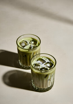 Top of view of two textured glass cups filled with iced matcha latte.