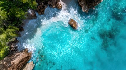 Breathtaking aerial view of turquoise waters crashing against a rocky shoreline reveals nature's dynamic beauty and the enchanting contrast between land and sea.