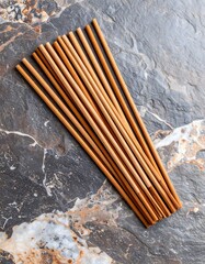 Artistic arrangement of bamboo incense sticks on a textured granite surface with earthy tones