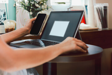 Business woman hands using cell phone while working on laptop.