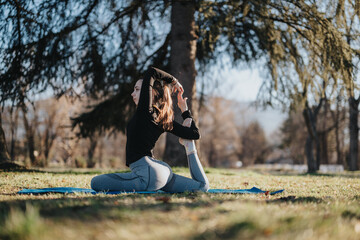 A person is engaged in a yoga pose outdoors in a park, with a serene background and sunlight. The...