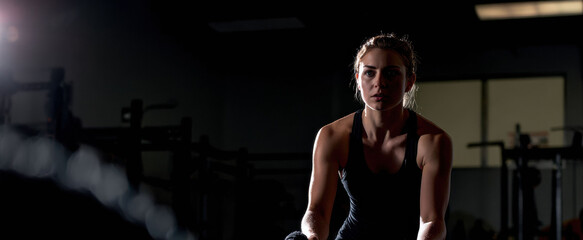A young athletic woman with a toned physique performs crossfit exercises with a rope in the gym, preparing for her competition.