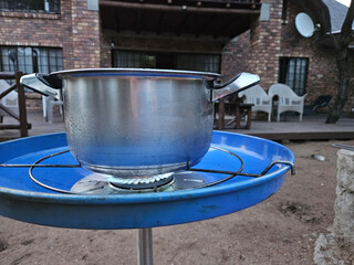 Blue container with a pot on top of it. The pot is on a stove during safari in park in South Africa