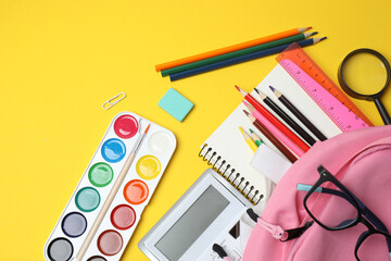 Children school supplies flat lay on yellow background with copy space