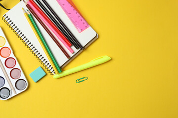 Children school supplies flat lay on yellow background with copy space
