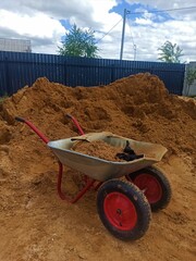 A wheelbarrow with a shovel and a pile of gravel