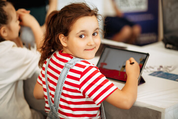 Little girl drawing on digital tablet using a digitized pen. Children's engagement of digital...