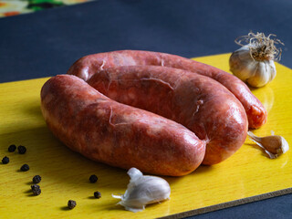 Raw pork meat sausages, black pepper, garlic. Raw sausages for grill on wood desk.