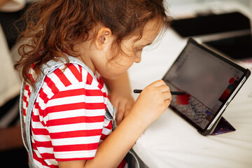 Little girl drawing on digital tablet using a digitized pen. Children's engagement of digital...